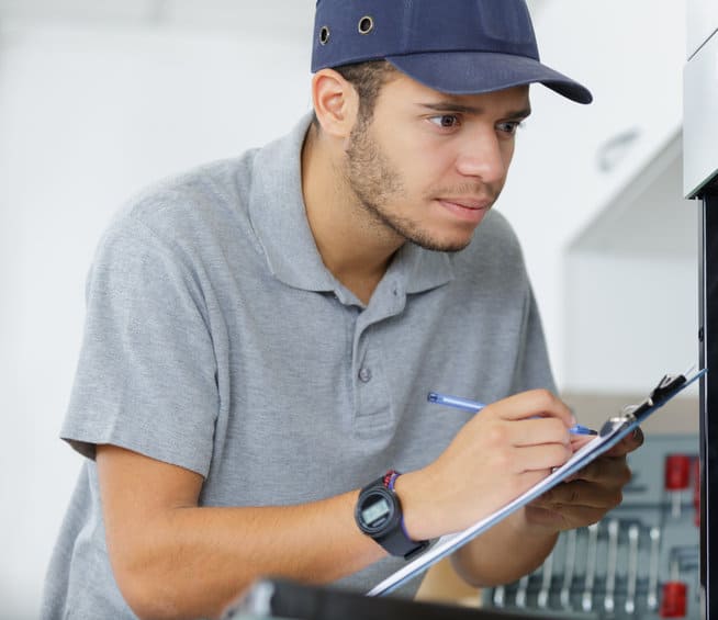 young male electrician in overall writing on clipboard